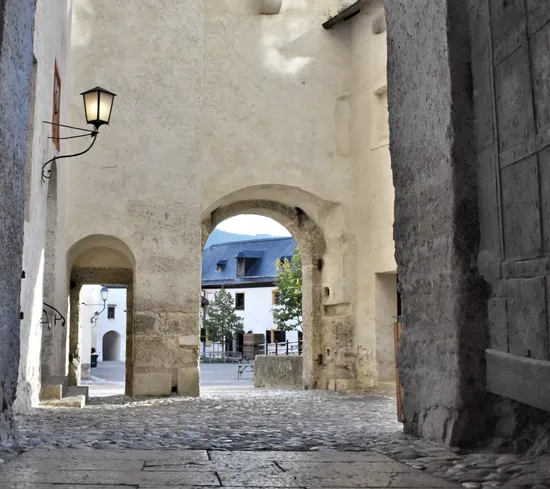 Steinbogen mit Laterne führt zu einem Kopfsteinpflasterhof und historischen Gebäuden